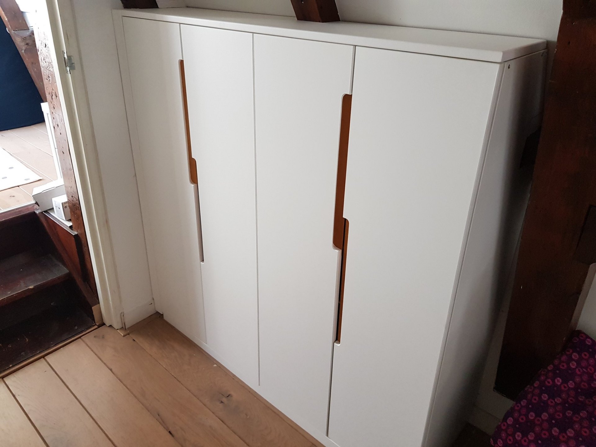 Compacte witte kast met warme houten greepuitsparingen