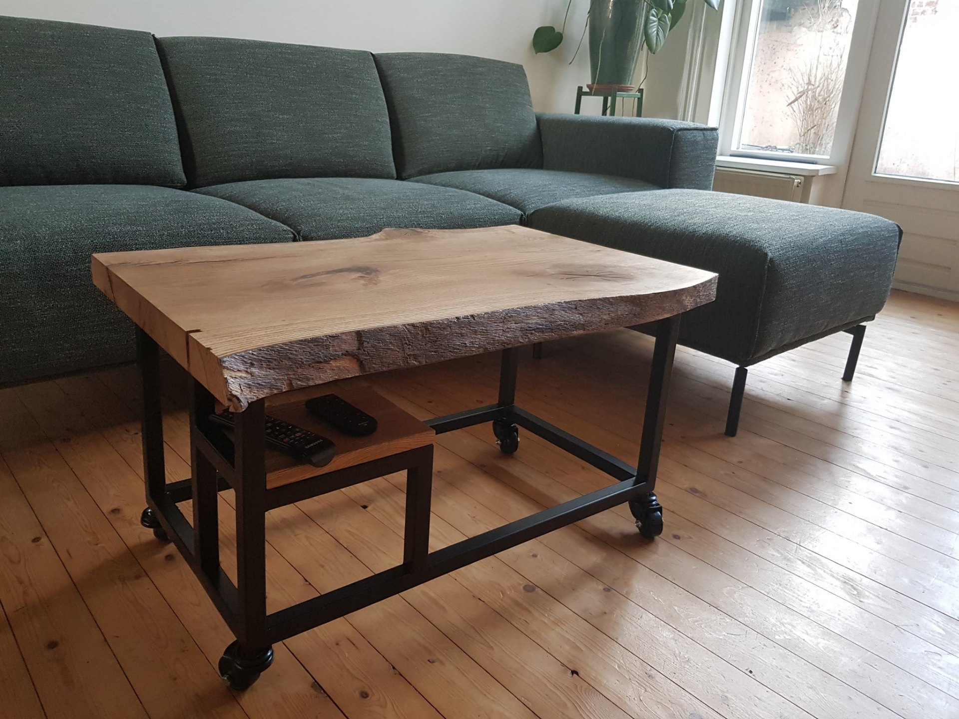 Salontafel met live-edge eiken blad op zwart stalen onderstel met wielen