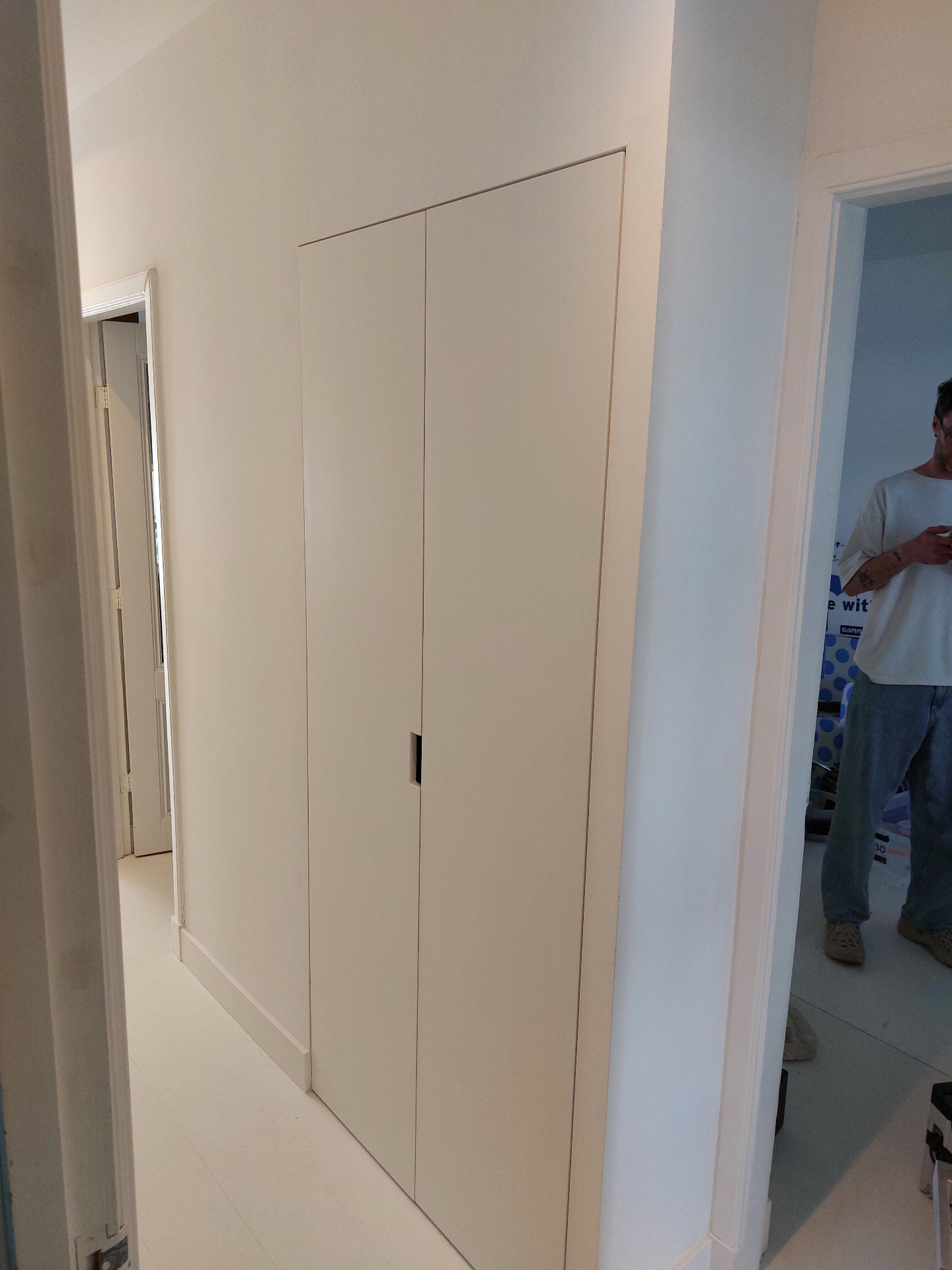 Strakke witte inbouwkast in de hal met verzonken greep