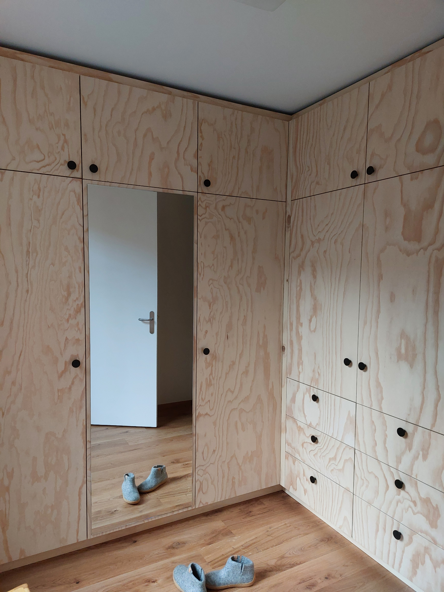 Plywood hoekkast met spiegeldeur en zwarte ronde knoppen