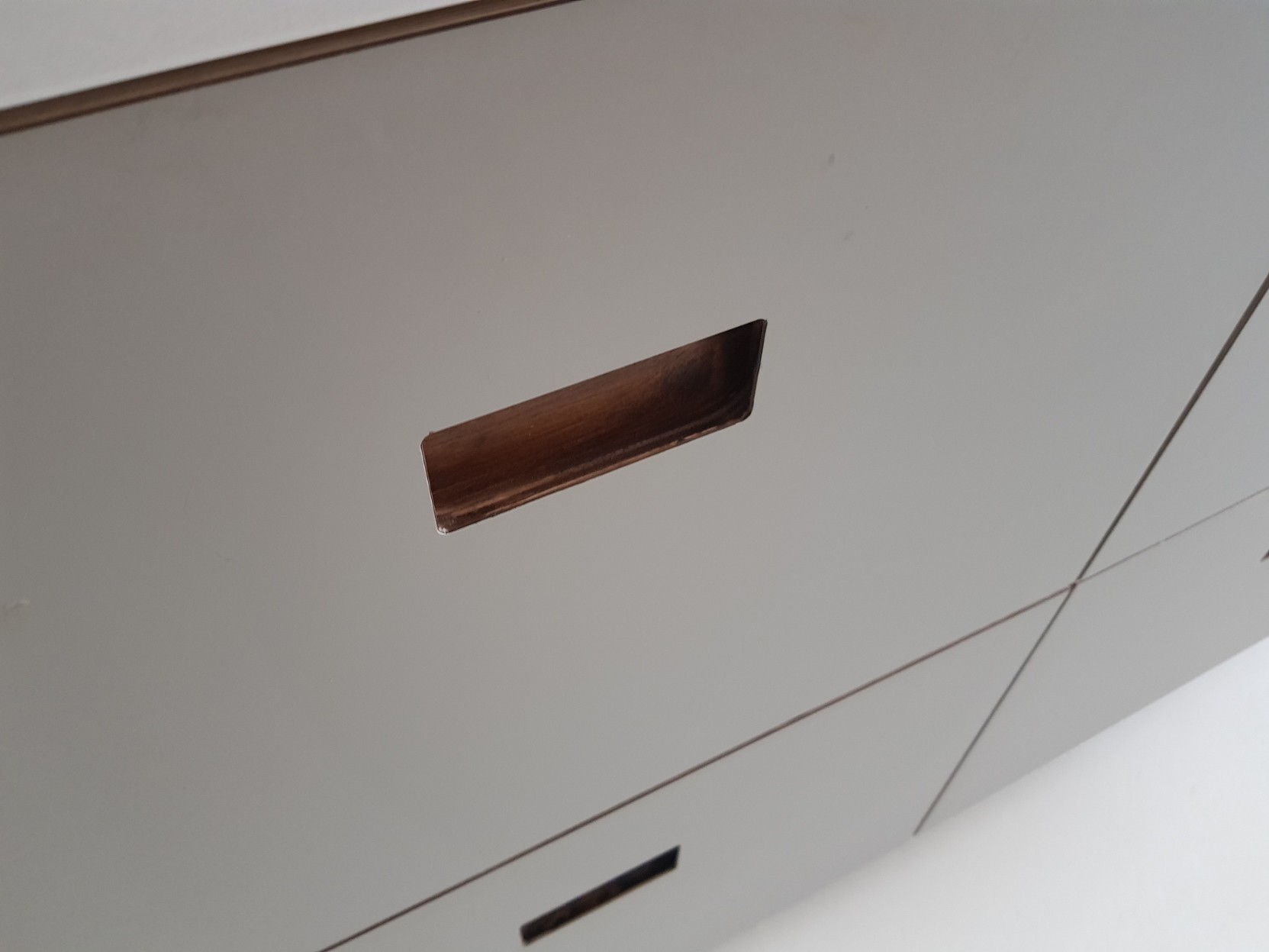 Detail van verzonken houten greep in witte Fenix kastdeur