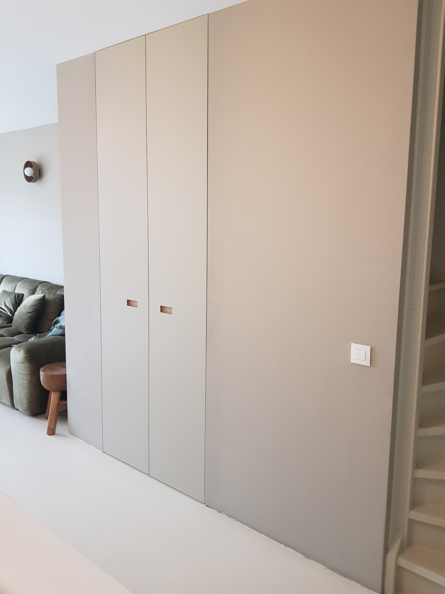 Vloer-tot-plafond witte inbouwkast met vier deuren en verzonken rechthoekige greep