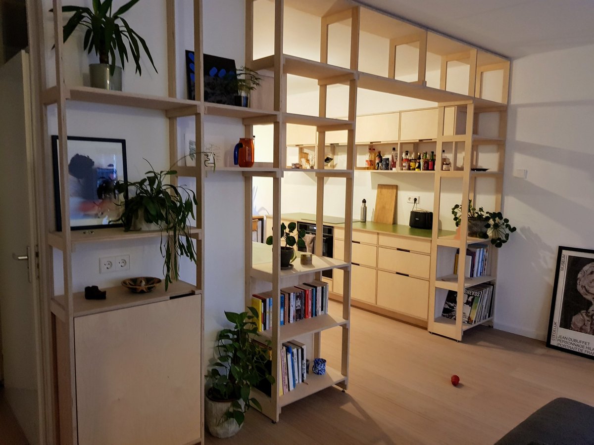 Plywood keuken met groen werkblad achter een open rasterkast als roomdivider