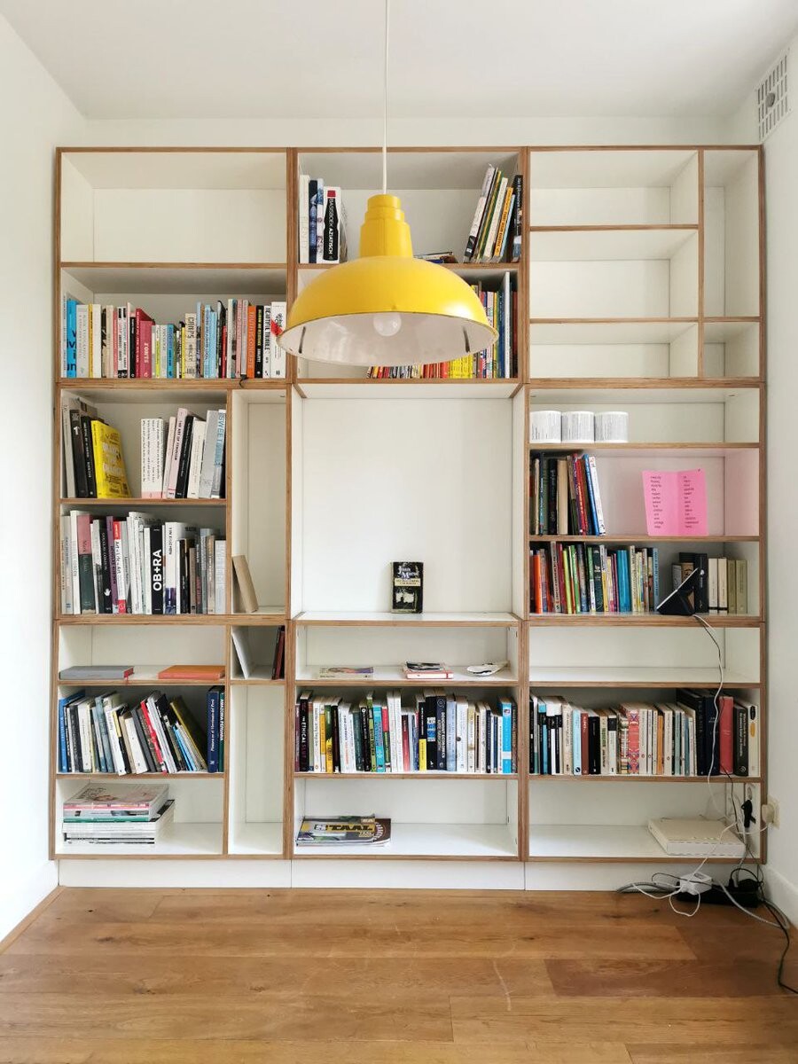Open multiplex boekenkast met grote middennis en gele hanglamp