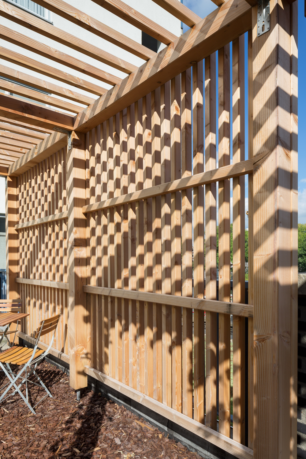 Detail van douglas pergola met diagonaal latwerk en schaduwspel